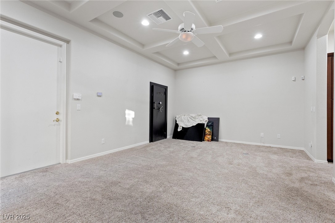 1911 Alcova Ridge Drive Las Vegas, NV 89135 - Photo 32 of 43 Unfurnished living room featuring visible vents, a ceiling fan, beam ceiling, carpet flooring, and coffered ceiling