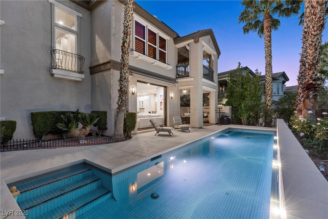 1911 Alcova Ridge Drive Las Vegas, NV 89135 - Photo 34 of 43 Back of house at dusk featuring a patio, a fenced in pool, a balcony, and stucco siding