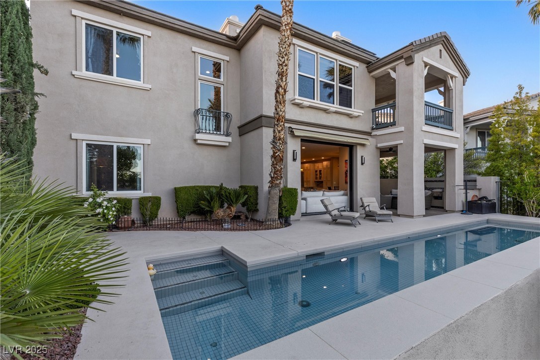 1911 Alcova Ridge Drive Las Vegas, NV 89135 - Photo 37 of 43 Back of property featuring a balcony, an outdoor pool, stucco siding, an outdoor living space, and a patio area