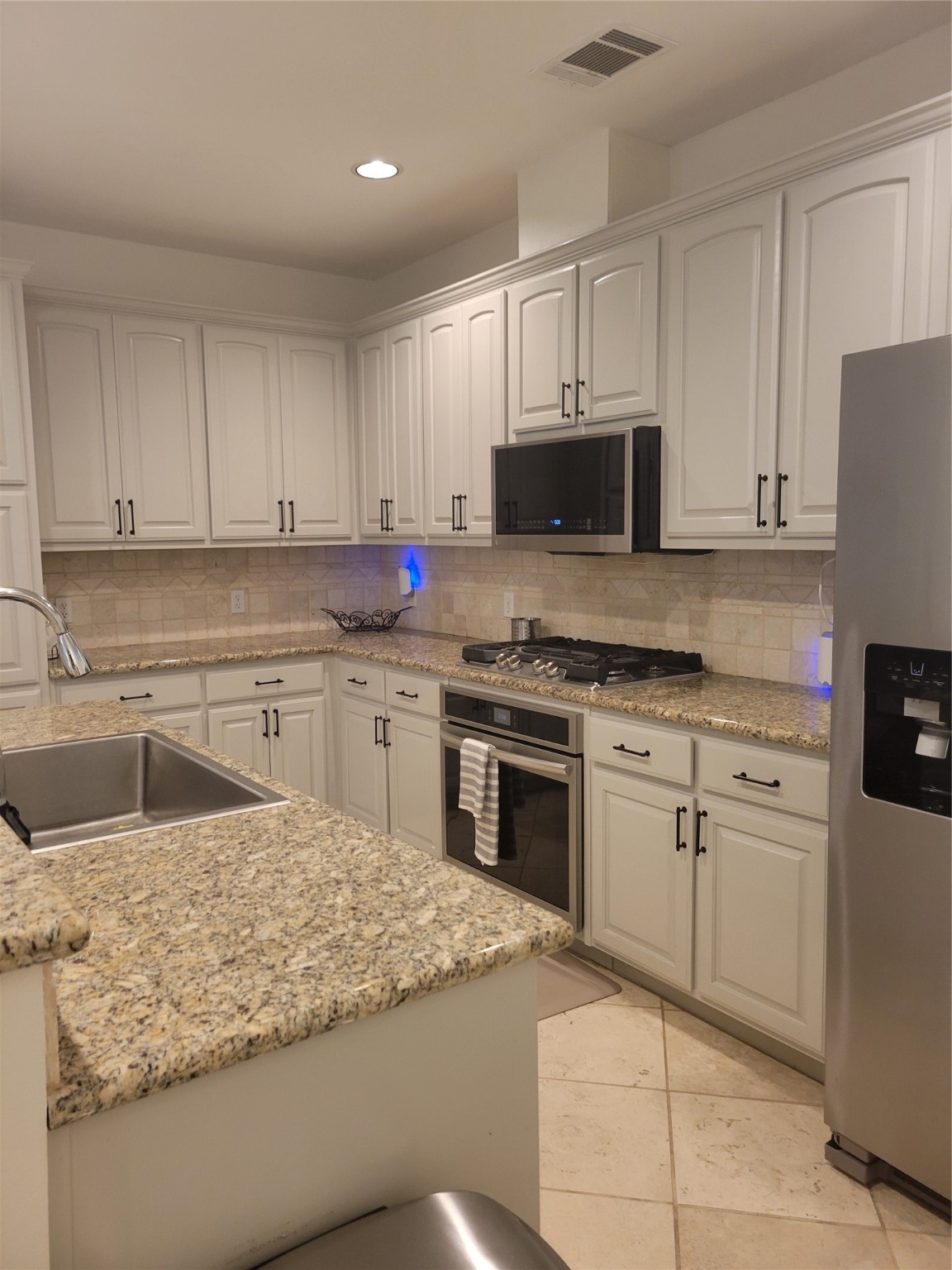 3203 Tom Green Street, Unit 3A Austin, TX 78705 - Photo 13 of 33 a kitchen with granite countertop a sink stainless steel appliances and white cabinets