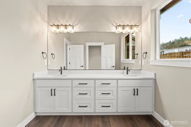 a spacious bathroom with double sink a mirror a window and a bathtub