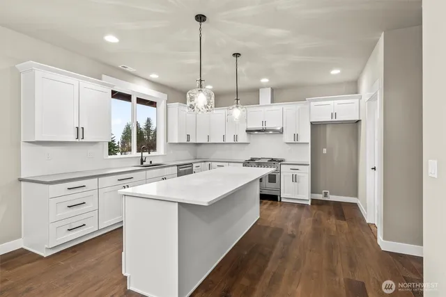 a large white kitchen with kitchen island a white cabinets and wooden floor