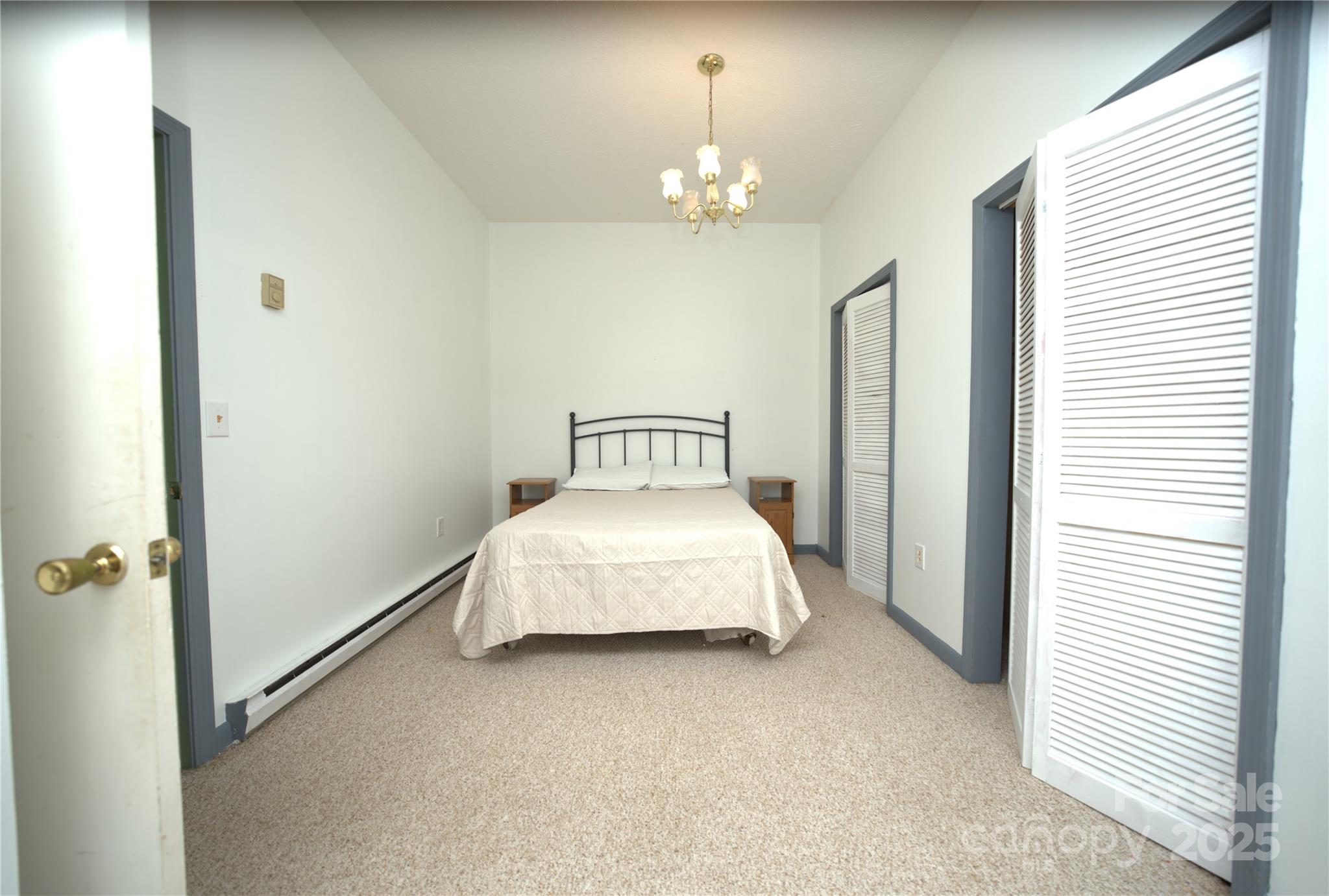 218 McGuffey Ridge Road Gerton, NC 28735 - Photo 28 of 29 a spacious bedroom with a bed and a chandelier