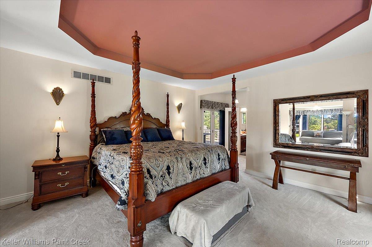 69069 Campground Road Romeo, MI 48065 - Photo 43 of 78 Recessed tray ceiling with accent color, light-toned wall paint, gray carpet flooring, decorative wall sconces, and double-door balcony access