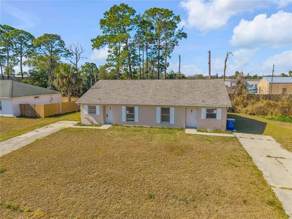 an aerial view of residential houses with outdoor space and trees