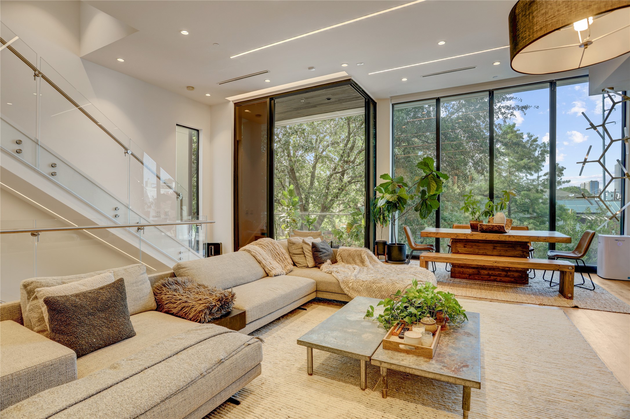1807 Indiana Street Houston, TX 77006 - Photo 15 of 35 Living Area & Balcony Entry: Sun-drenched second-floor living space highlighting the expansive floor-to-ceiling glass windows, wide-plank flooring, and a modern glass-panel staircase adjacent to the balcony sliding door.