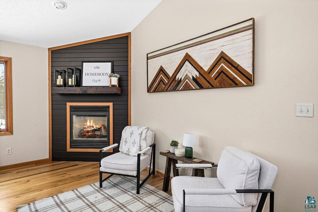 2783 Lauren Road Duluth, MN 55804 - Photo 15 of 47 Living area with a large fireplace, vaulted ceiling, and light wood-style floors