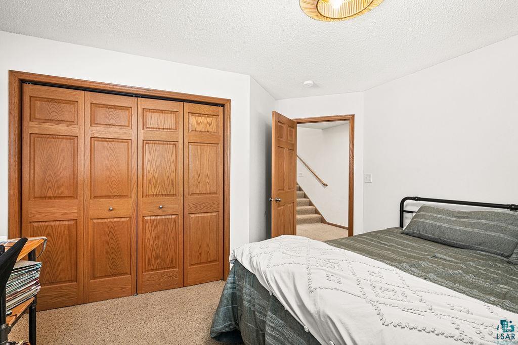 2783 Lauren Road Duluth, MN 55804 - Photo 36 of 47 Bedroom featuring light colored carpet, a textured ceiling, and a closet