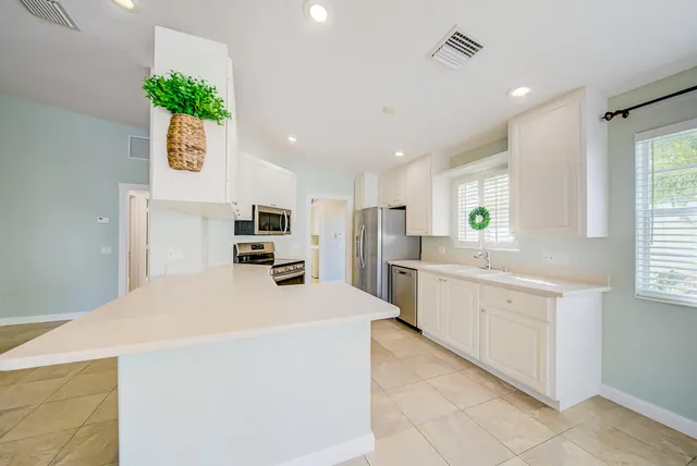 a kitchen with white cabinets and sink