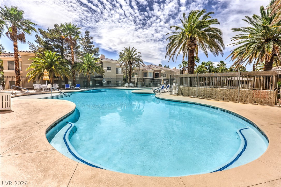 9050 West Warm Springs Road, Unit 2033 Las Vegas, NV 89148 - Photo 24 of 30 An inviting resort-style pool with integrated steps beckons, surrounded by lush palm trees and private seating areas.