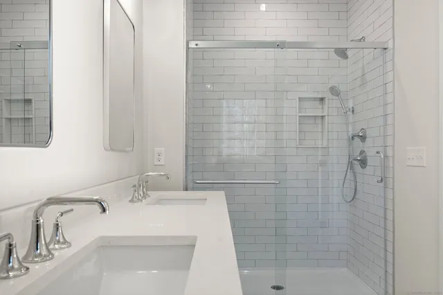 a bathroom with a sink a toilet a mirror and shower