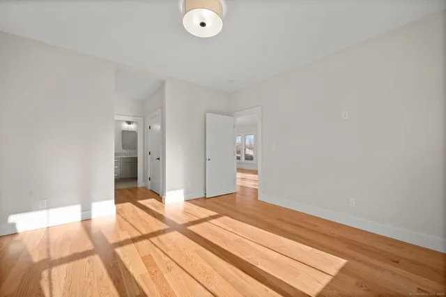 a large white kitchen with a stove a sink dishwasher and a refrigerator with wooden floor