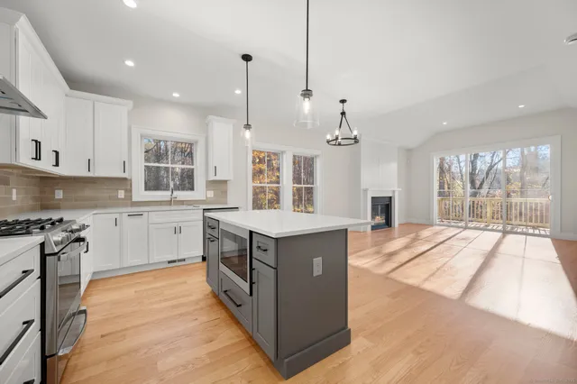 a kitchen with stainless steel appliances granite countertop a stove a sink dishwasher a refrigerator and white cabinets with wooden floor