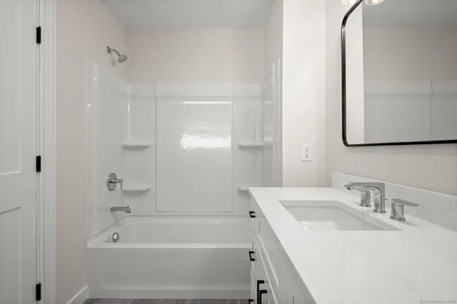 a bathroom with a sink tub vanity and a mirror
