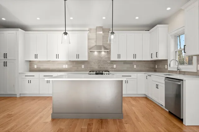 a kitchen with stainless steel appliances granite countertop a refrigerator a stove a sink and white cabinets with wooden floor