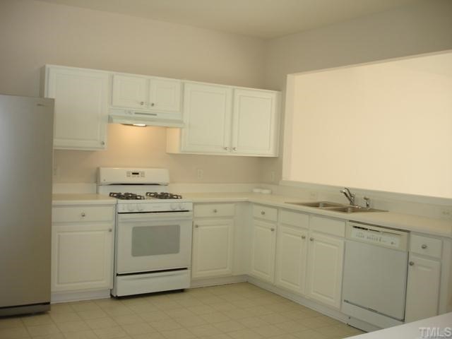 4325 Vienna Crest Drive Raleigh, NC 27613 - Photo 10 of 12 a kitchen with white cabinets and white appliances