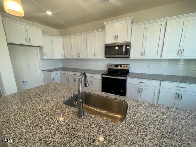 912 Channel Drop Loop Zebulon, NC 27597 - Photo 11 of 25 a kitchen with granite countertop a sink stove and white cabinets