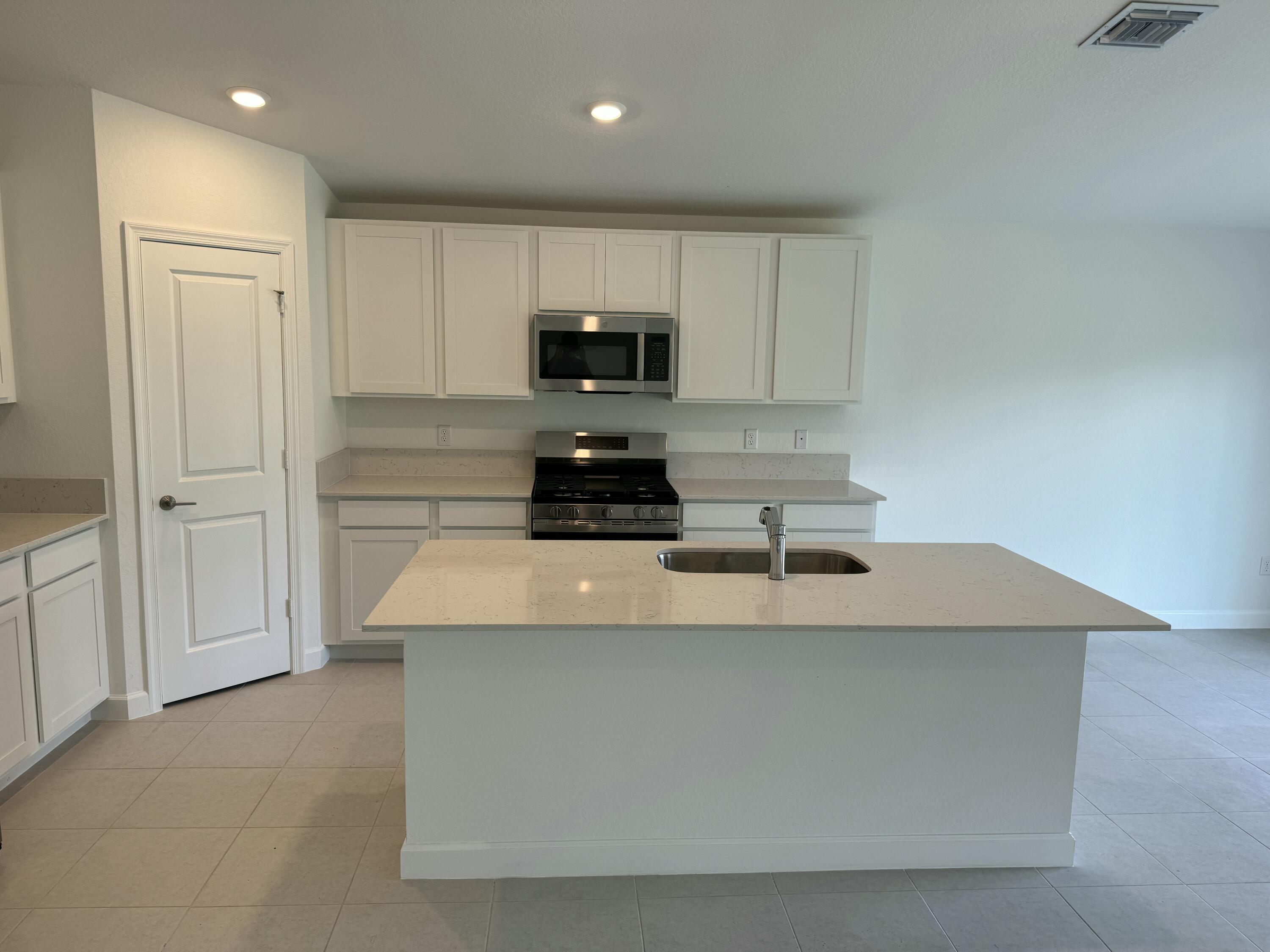 10445 Northwest Suncrest Loop Port Port St. Lucie, FL 34987 - Photo 17 of 45 a kitchen with kitchen island a sink stainless steel appliances and cabinets