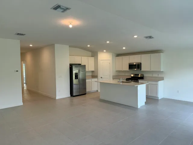 a large kitchen with stainless steel appliances kitchen island a sink a refrigerator and a stove top oven