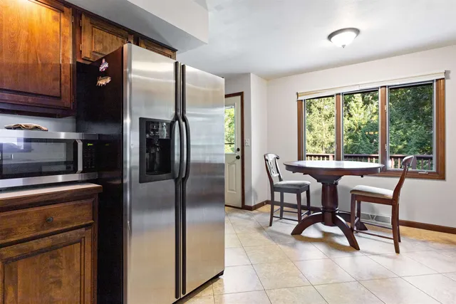 a kitchen with stainless steel appliances granite countertop a table chairs and a refrigerator