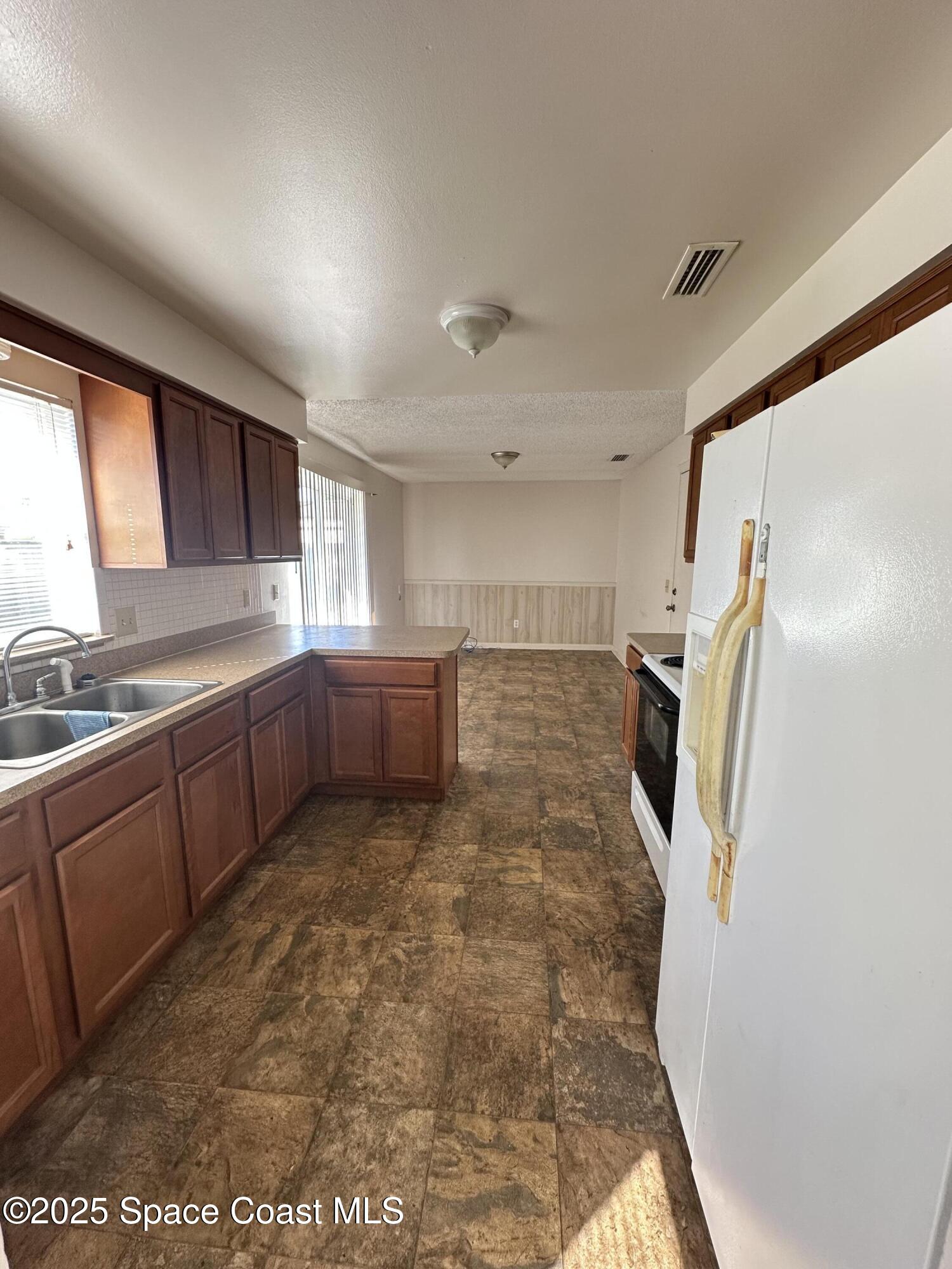 905 Grant Road Titusville, FL 32780 - Photo 19 of 30 a kitchen with stainless steel appliances granite countertop a refrigerator and a sink