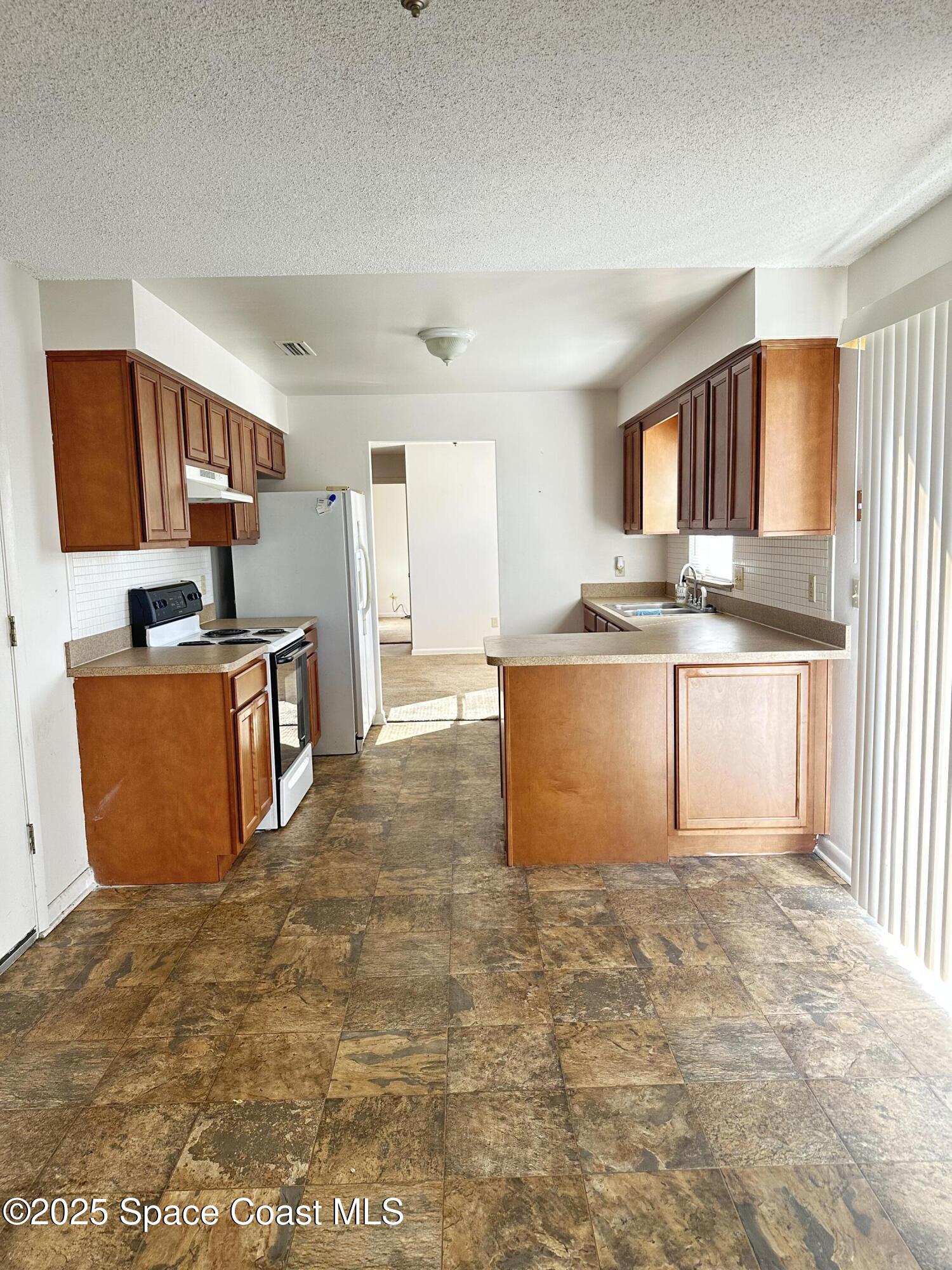 905 Grant Road Titusville, FL 32780 - Photo 20 of 30 a kitchen with stainless steel appliances granite countertop a stove top oven a sink a counter space and cabinets