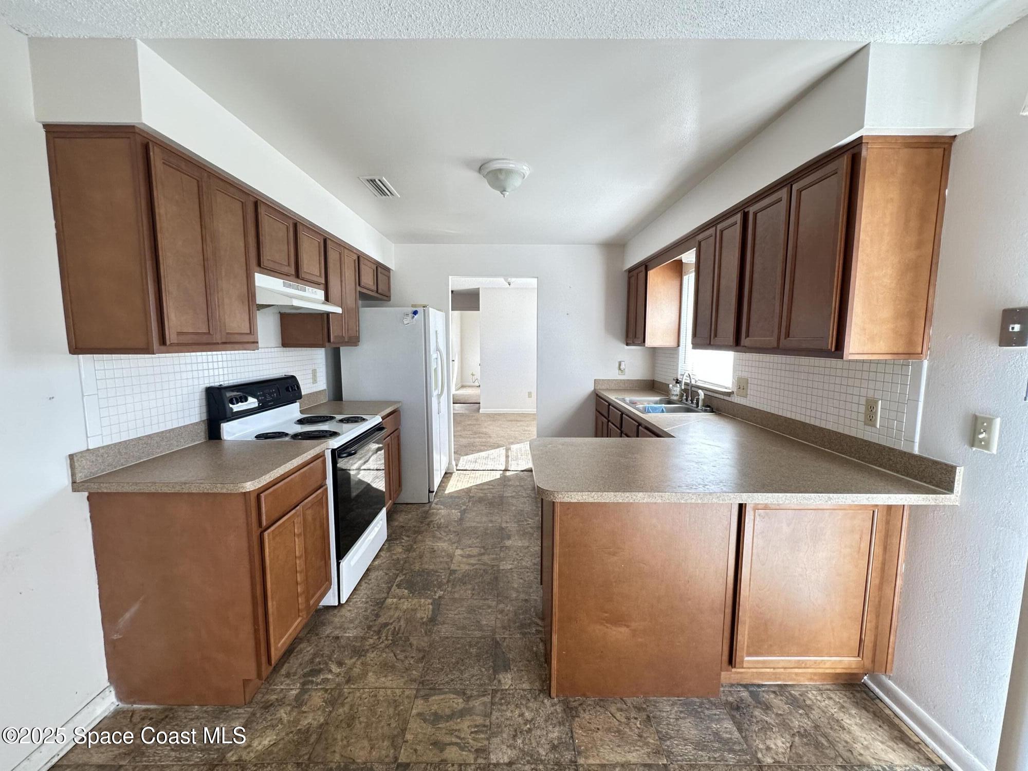 905 Grant Road Titusville, FL 32780 - Photo 22 of 30 a kitchen with stainless steel appliances granite countertop a stove a sink a refrigerator and a microwave