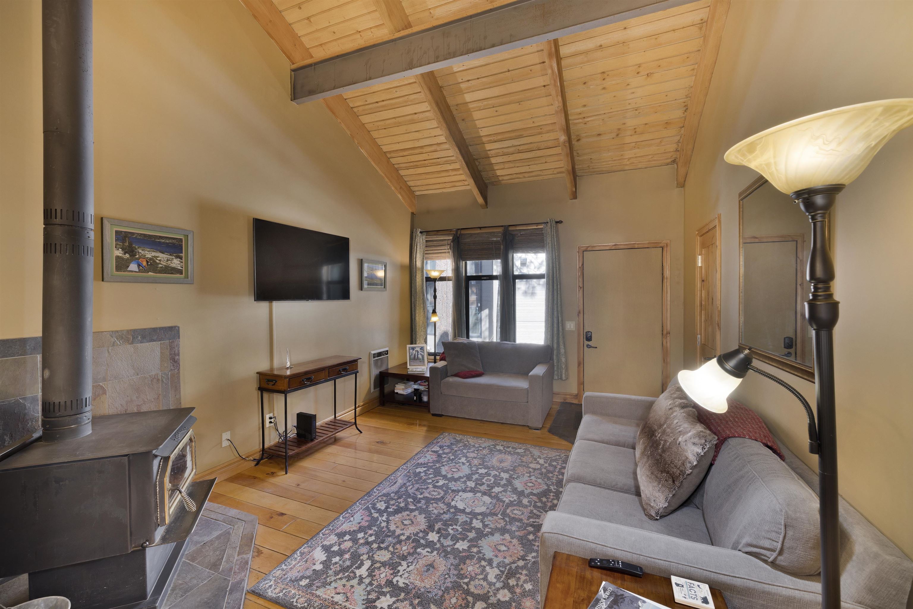 2252 Meridian Boulevard, Unit 32 Mammoth Lakes, CA 93546 - Photo 3 of 31 Living room with a high wooden beamed ceiling, a wood stove, and light wood-style floors