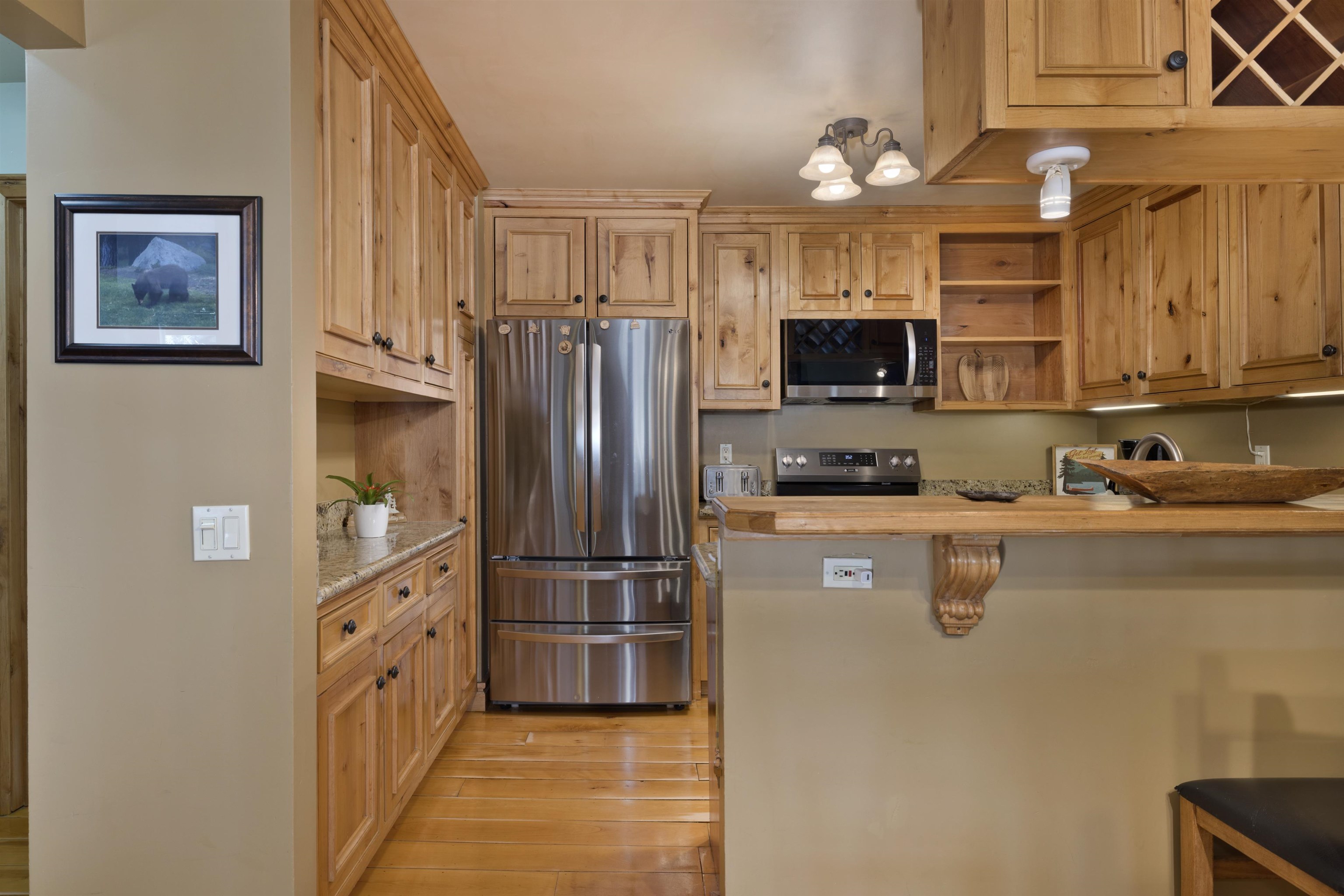 2252 Meridian Boulevard, Unit 32 Mammoth Lakes, CA 93546 - Photo 7 of 31 Kitchen with stainless steel appliances, a kitchen breakfast bar, open shelves, a peninsula, and light wood finished floors