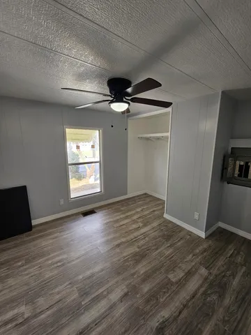 an empty room with wooden floor a ceiling fan and windows