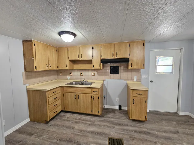 a kitchen with stainless steel appliances granite countertop a sink a stove a refrigerator cabinets and a window