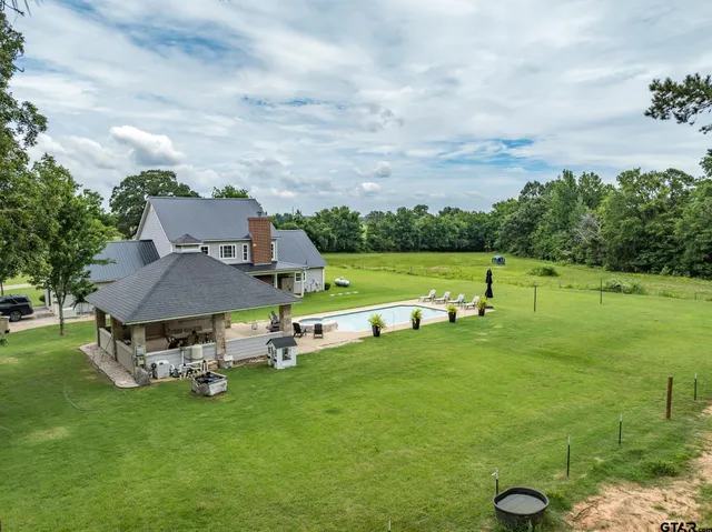 a view of pool with table and chairs under an umbrella