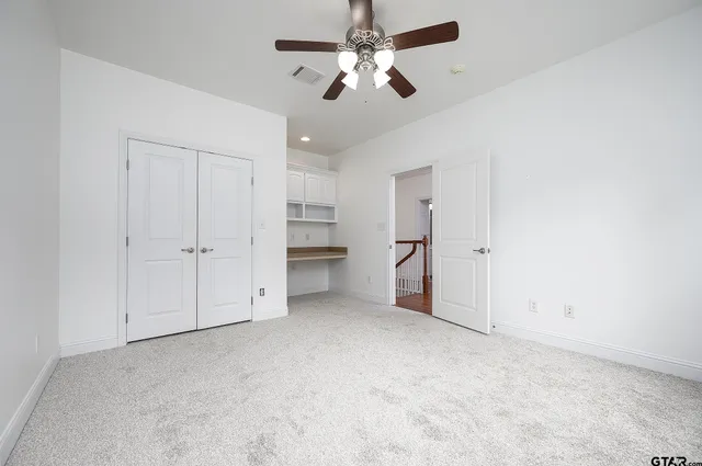 an empty room with closet and a chandelier fan