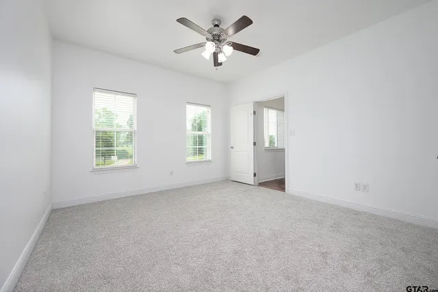 an empty room with windows and ceiling fan
