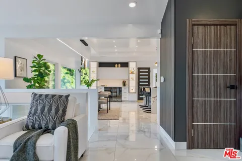 a large kitchen with stainless steel appliances kitchen island a large counter top a stove a chimney a sink and a refrigerator