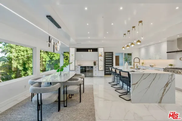 a large kitchen with stainless steel appliances kitchen island a large counter top a stove a chimney a sink and a refrigerator