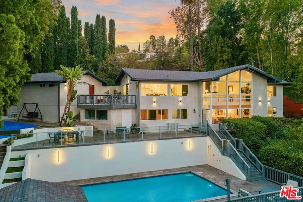 a view of a house with pool lawn chairs and a barbeque