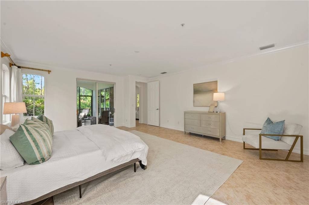 2886 Castillo Court, Unit 101 Naples, FL 34109 - Photo 20 of 45 a spacious bedroom with a bed a table and chair
