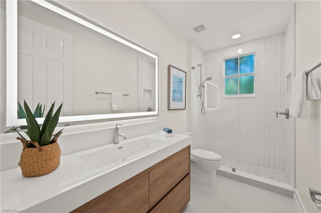 2886 Castillo Court, Unit 101 Naples, FL 34109 - Photo 24 of 45 a bathroom with a double vanity sink toilet and a mirror