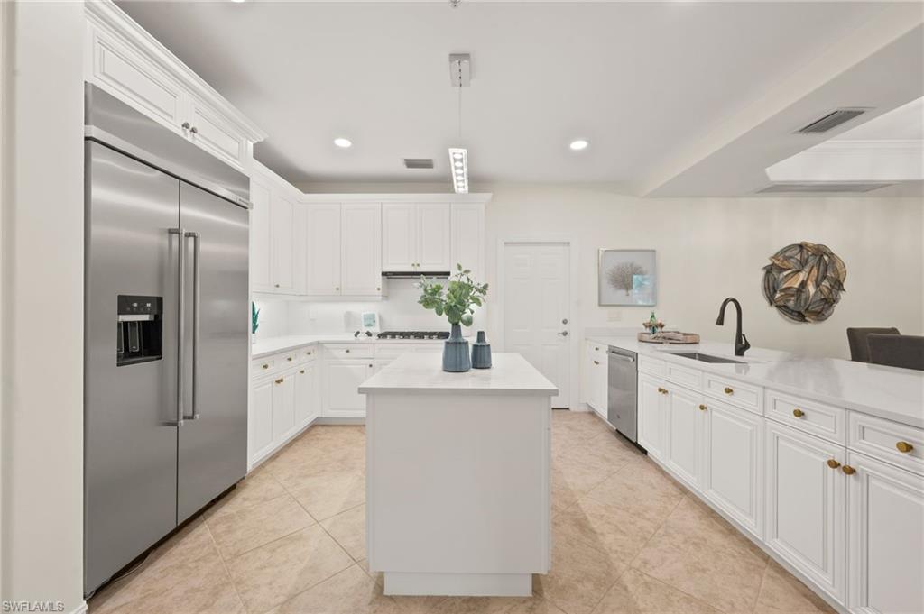 2886 Castillo Court, Unit 101 Naples, FL 34109 - Photo 7 of 45 a large kitchen with stainless steel appliances kitchen island granite countertop a sink and refrigerator