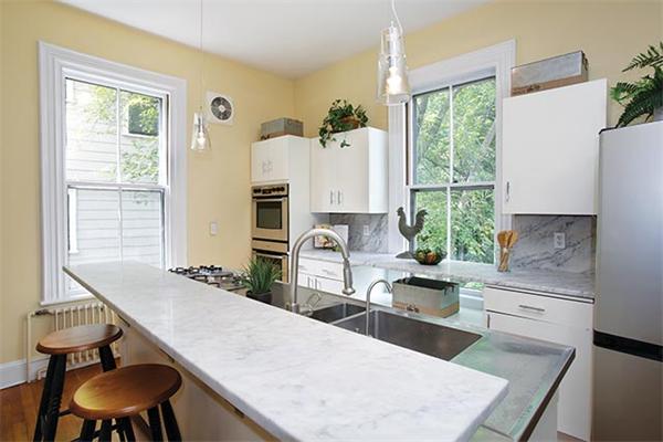 273 Walnut Street Brookline, MA 02445 - Photo 5 of 10 a kitchen with granite countertop a stove a sink a dining table and chairs