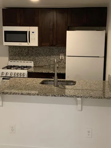 a kitchen with granite countertop a refrigerator and a stove