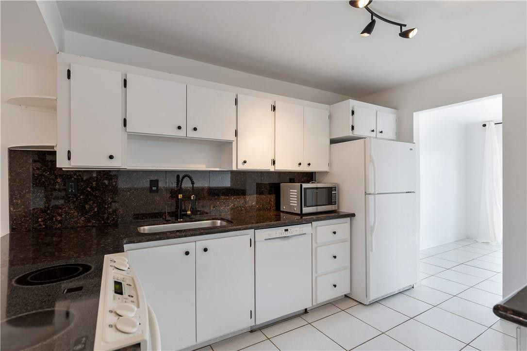 9717 North New River Canal Road, Unit 409 Plantation, FL 33324 - Photo 8 of 20 a kitchen with white cabinets a sink and white appliances