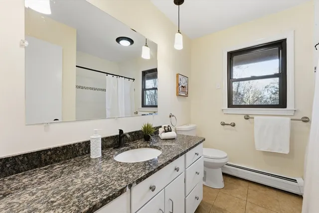 a bathroom with a granite countertop sink a toilet and mirror