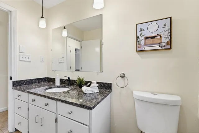 a bathroom with a granite countertop sink a toilet and a mirror