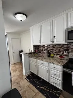 a kitchen with granite countertop a stove a sink and a microwave