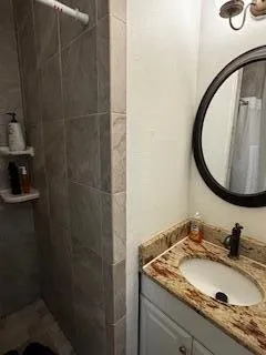 a bathroom with a granite countertop sink a mirror and shower