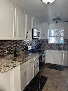 a kitchen with granite countertop white cabinets and white appliances