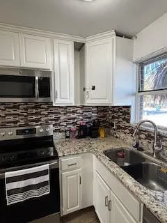 a kitchen with granite countertop a sink stove and microwave
