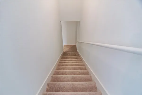 a view of a hallway with wooden floor and a bathroom